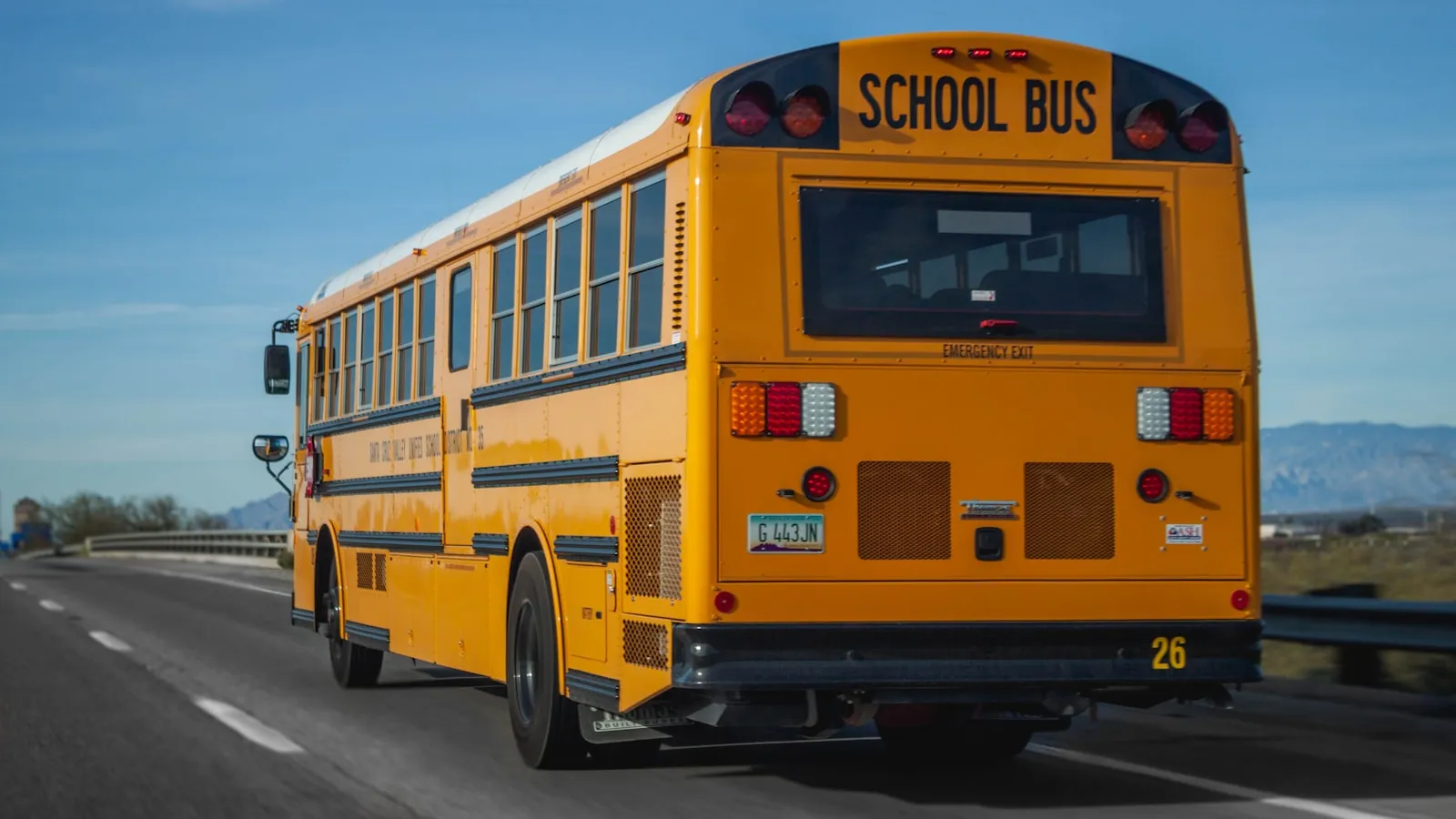 A yellow school bus on the highway, seen from behind